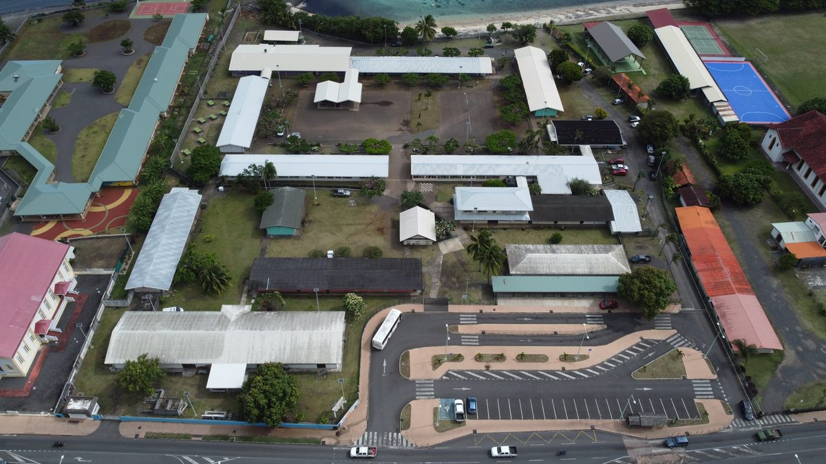 Vue aérienne du collège de Papara : les bâtiments blancs alignés autour de la cour, le lagon et la plage en arrière-plan.